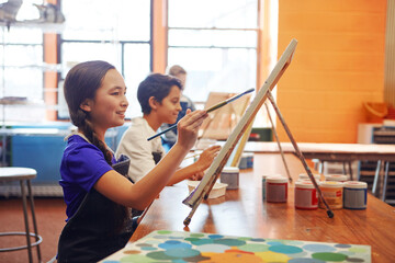 Smile, children and painting in class for art, creative talent and development in school. Education, students drawing and kids with watercolor for learning, artwork and sketch on canvas with brush