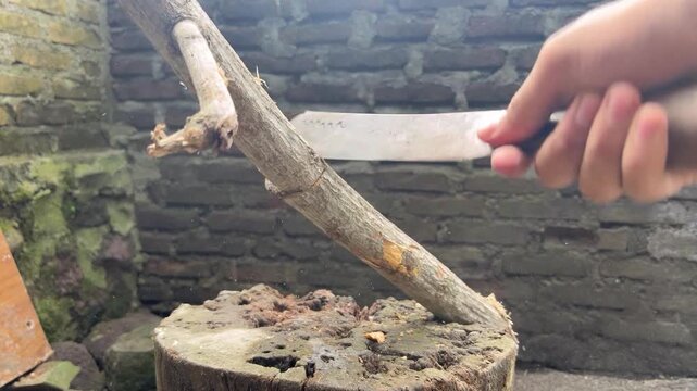 A close-up video of a hand swinging a machete to chop wood. The sharp, rhythmic movements suggest a powerful and authentic manual labor activity.