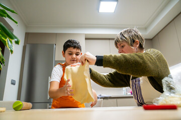 Woman and boy preparing food together, bonding over baking in a modern home kitchen, learning cooking skills