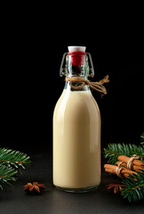 Festive Christmas eggnog in a bottle isolated on a black background, traditional Christmas drink
