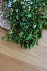 Bunch of Misteletoe branches with white berries on wooden table with copy space. Viscum album 