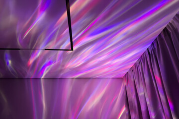 Colorful light reflections of projector on a textured purple wall and ceiling, creating a vibrant atmosphere with flowing patterns and soft drapery enhancing the visual experience of the space