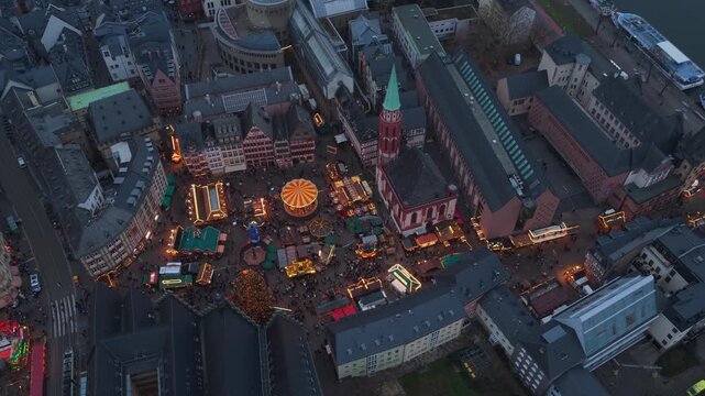 High angle view circling over illuminated christmas market at Romerberg square in Frankfurt, Germany, with crowds of people