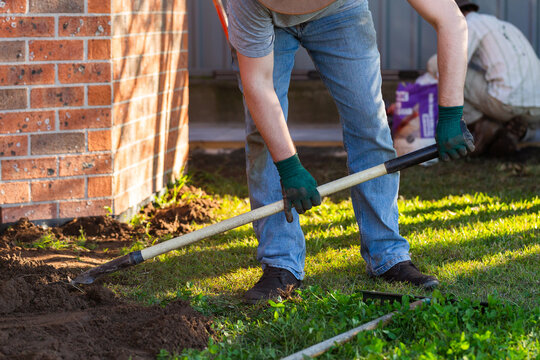 Men working together in front yard to level ground solving drainage issues