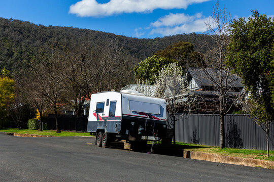 caravan parked on roadside outside colorbond fence in town