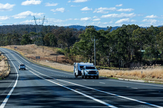 Car towing caravan on Aussie country road in sunlight