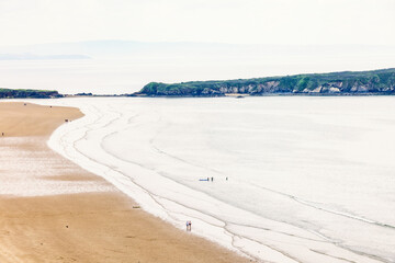 Aerial view at a sand beach with walking people and rolling waves