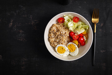 Healthy breakfast. Bowl of oatmeal and fresh vegetables and boiled egg. Top view.
