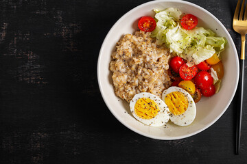 Healthy breakfast. Bowl of oatmeal, fresh vegetables, boiled egg. Top view.