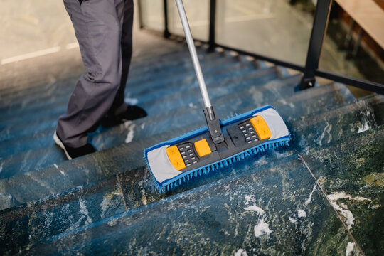 Putzkraft wischt die Treppe mit Wischmopp