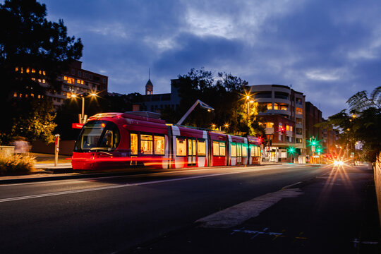 Long exposure red light rail train waiting at Newcastle Beach stop tram station at night 