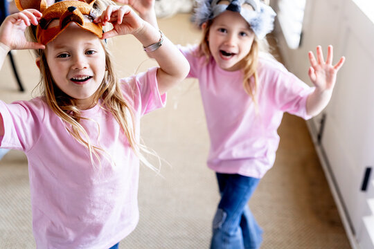 Happy twin girls holding animal masks atop their heads