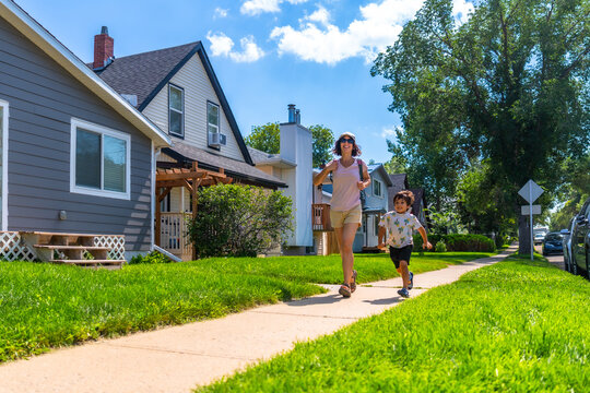 Mother and son running on sidewalk in suburban neighborhood
