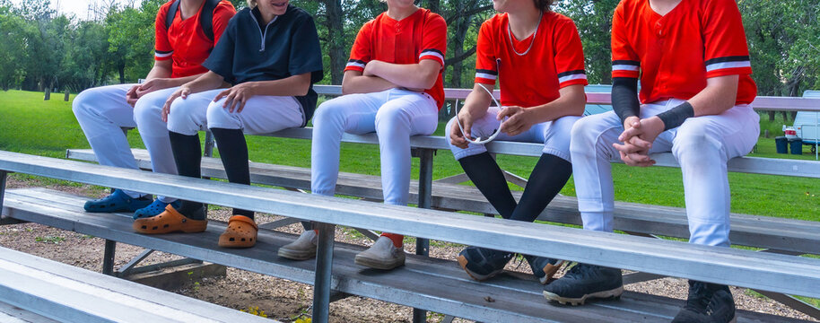 Baseball teammates relaxing on bleachers after game - Powered by Adobe