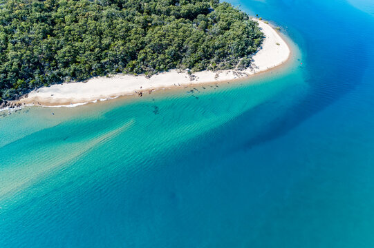 Tropical forest and sandy point along a turquoise estuary