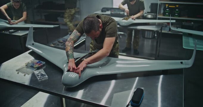 Techs Building Unmanned Aircraft For Strategic Advantage. Technicians in Cutting Edge Facility Building Unmanned Aircraft. Concept Advanced Technological Production For Defense and National Security.