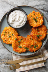 Sweet Potato Hash Browns served with sour cream closeup on the plate on the table. Vertical top view from above
