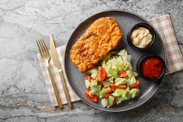 Sicilian steak includes any good cut of steak breaded with a mixture of bread crumbs and Parmesan cheese and sauteed in olive oil closeup on the plate on the table. Horizontal top view from above