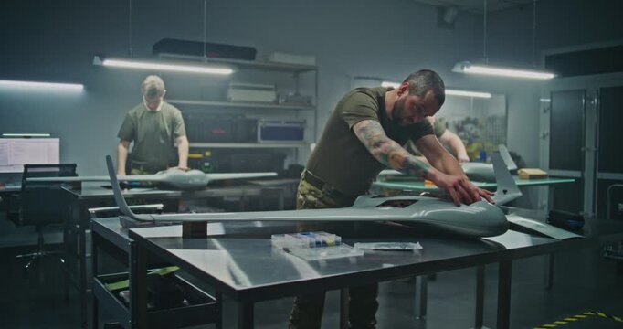 Concentrated Engineer Assembling Drone Internal Components, While Professional Team Works on Similar Units in Background. Concept of Individual Precision Within Collective, High Tech Production Line.