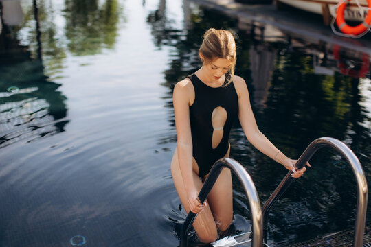 Young woman exiting swimming pool using ladder - Powered by Adobe