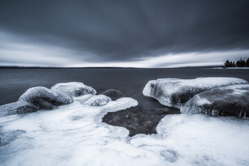 Ice covers the shoreline at lake Femunden in Norway during a cloudy day