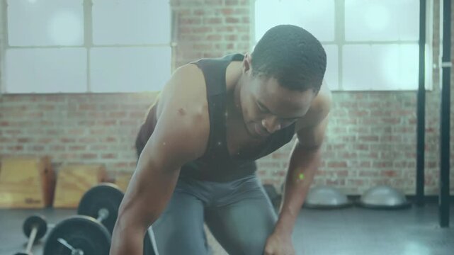 Male trainee performing one-arm rows starting bent over bracing hand, pulling dumbbell for strength