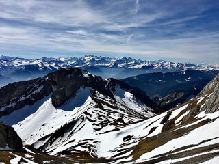 Majestic snow-covered peaks and rugged cliffs of Mount Pilatus under a clear blue sky in the Swiss Alps.