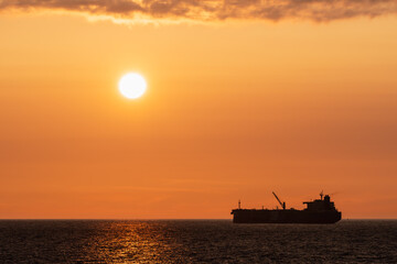 Golden Baltic Sea Sunset Silhouette of an Oil Tanker or Cargo Ship Cruising Near the Estonian Coastline with Bright Sun.