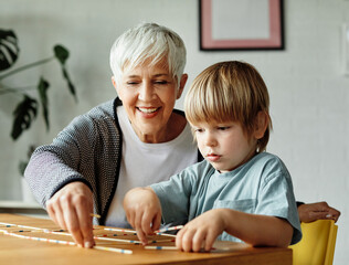 Portrait of grandmother and grandson having fun together playing board game pick-up sticks at home