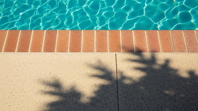 Vibrant blue swimming pool water with brick coping and dappled sunlight on the deck