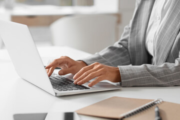 Young businesswoman working with laptop at desk in office, closeup