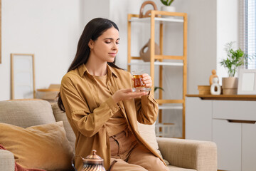 Young woman with Turkish tea sitting on sofa at home
