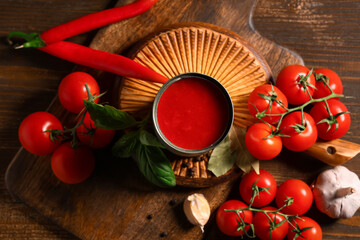 Tin can of tasty tomato paste and different ingredients on wooden background