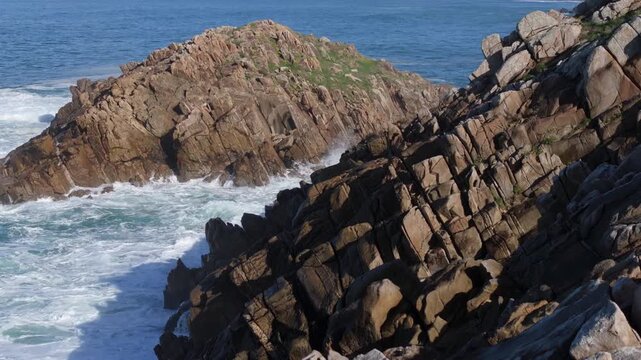 Foamy Waves Breaking Against The Rocks Of The Senda Azul (Paseo Mar&iacute;timo de Arteixo) In Arteixo, A Coru&ntilde;a, Spain. Aerial Pullback Shot