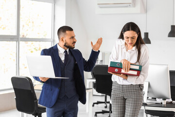 Female worker with folders and her angry boss in office