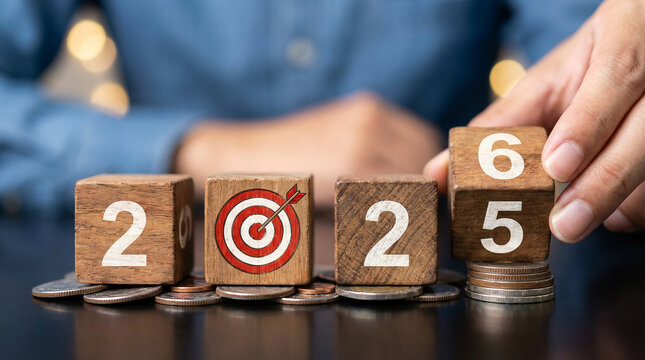 Hand setting 2025 goals with wooden blocks, target, and coins. Concept of financial planning, business strategy, success, and investment for the new year