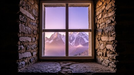 Old stone wall window looking out at majestic snow-capped mountains and purple sky at sunrise