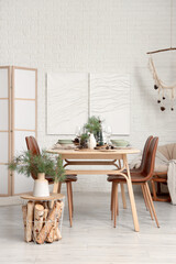 Interior of room with dining table, fir branches and paintings