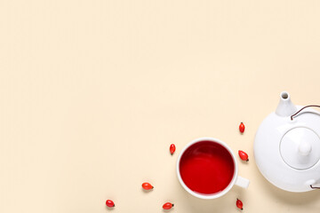 Cup and teapot of hot rose hip tea on beige background