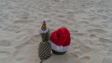 Santa Claus pineapple and watermelon couple wearing stylish sunglasses on the sand contrasting with the sea. wearing a christmas hat Christmas and New Year holiday ideas on the beach, Patong, Phuket