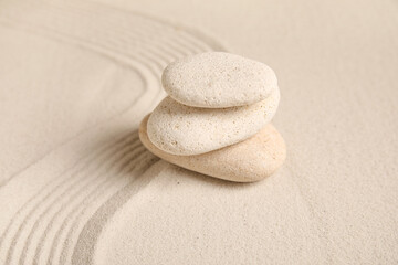 Composition with stack of spa stones and lines on sand as background, closeup. Zen concept