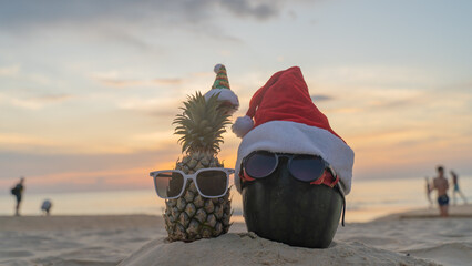 Santa Claus pineapple and watermelon couple wearing stylish sunglasses on the sand contrasting with the sea. wearing a christmas hat Christmas and New Year holiday ideas on the beach, Patong, Phuket