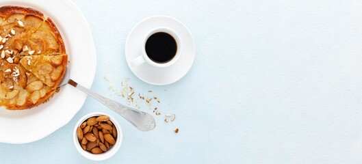 Apple pie tart with almonds and coffee cup on light blue background top view
