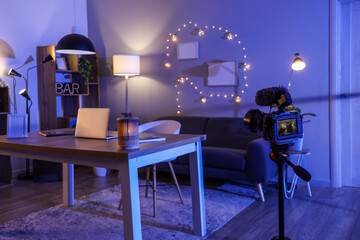 Interior of dark office with workplace, camera and glowing lamps