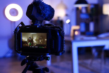 Interior of blogger's room with workplace and glowing lamps on camera screen at night, closeup