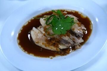 Tender Chinese steamed chicken served with rich soy-based sauce, topped with fried garlic, fresh cilantro, and sliced green onions for garnish.