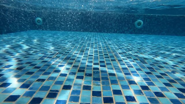 Underwater View of Swimming Pool Tiled Bottom and Water Surface