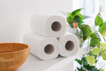 Shelf with rolls of paper towels on light wall in kitchen, closeup
