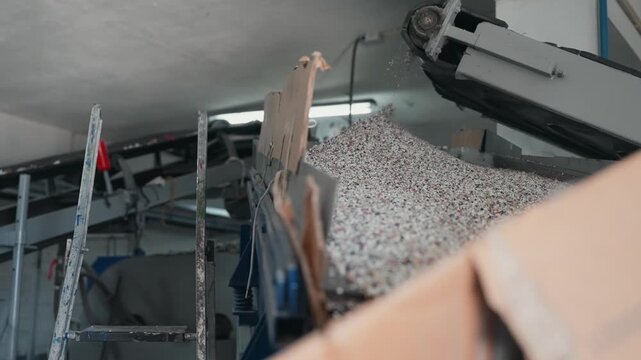 rubber granules falling from conveyor into pile inside busy factory setting
