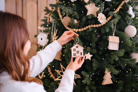 Personne decorant un sapin de Noel avec des ornements en bois et des lumieres douces